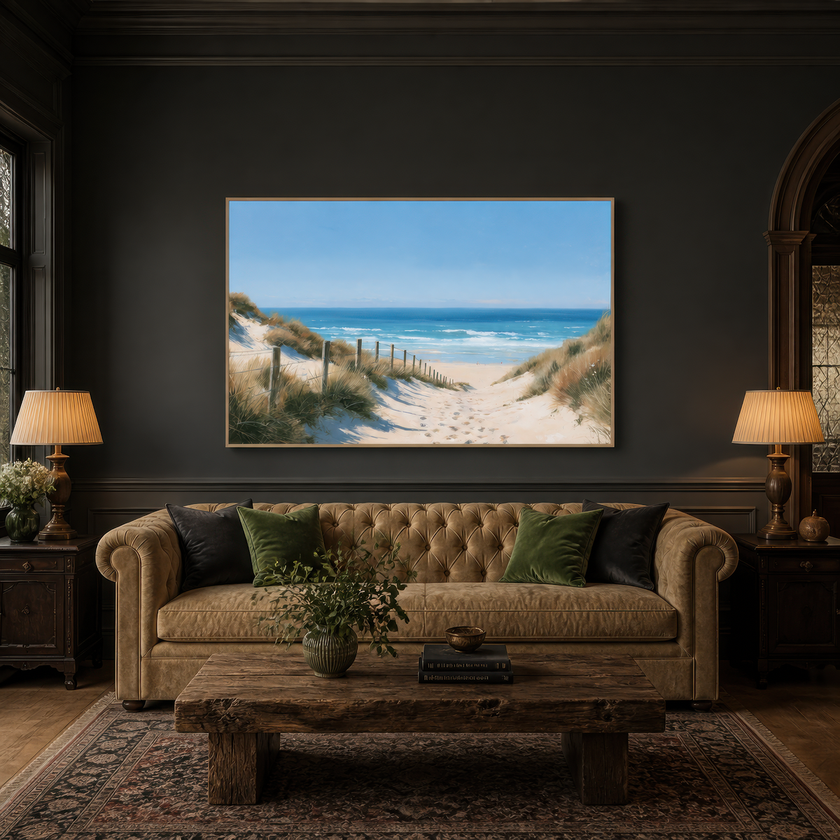 Wide dune path artwork above a tan tufted Chesterfield sofa on a dark charcoal wall