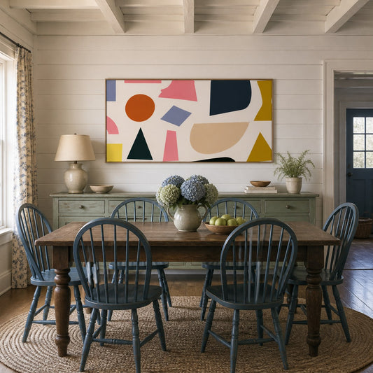 Wide rust, navy and mustard geometric abstract artwork above a sideboard in a dining room with blue Windsor chairs