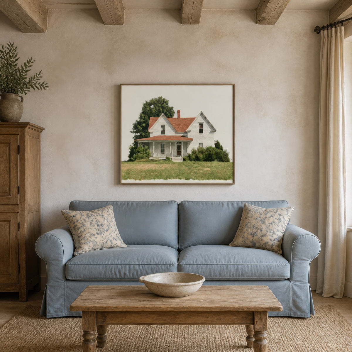 White farmhouse illustration above a pale blue sofa with floral pillows and a pine cabinet
