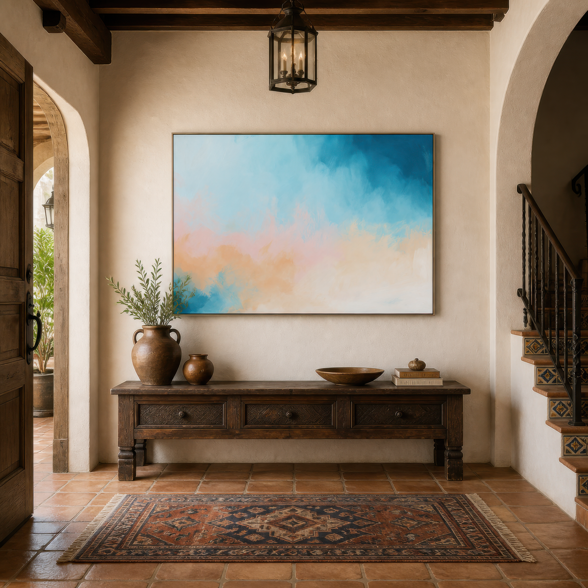 Large soft teal and apricot abstract artwork above a carved wooden console in an entryway beside a staircase