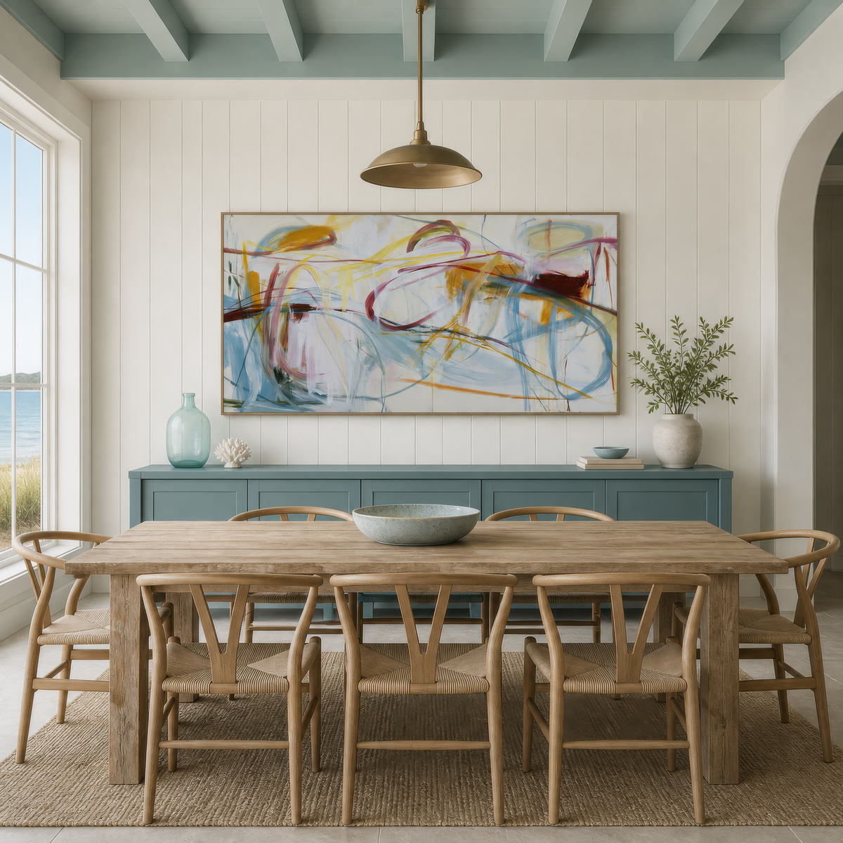 Wide mustard, burgundy and blue-gray loops abstract artwork above a blue sideboard in a dining room with a wooden table