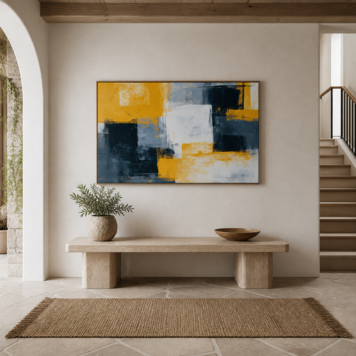 Large mustard yellow and charcoal color block abstract artwork above a stone bench in a white entryway beside a staircase