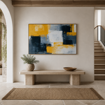 Large mustard yellow and charcoal color block abstract artwork above a stone bench in a white entryway beside a staircase