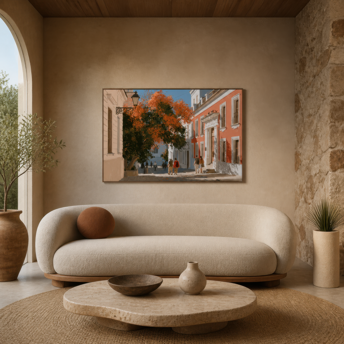 Mediterranean street scene above a cream curved sofa with a round stone table by a rock arch