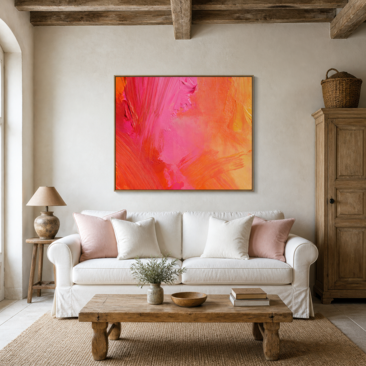 Coral pink brushstrokes above a white sofa with blush pillows and a pine cabinet