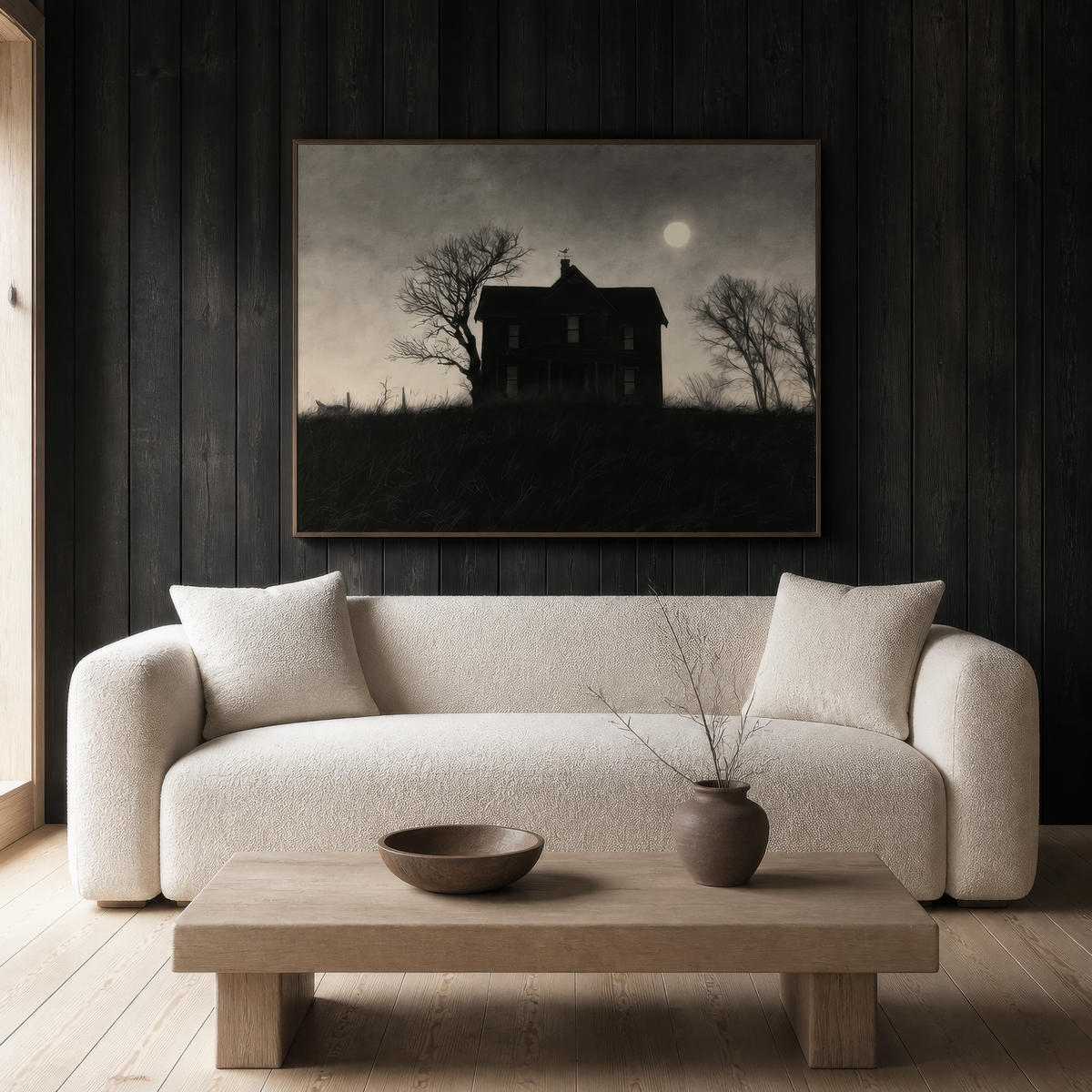 Moonlit farmhouse silhouette above a cream curved sofa on a dark timber plank wall