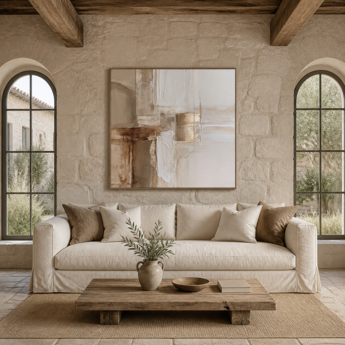 Square beige and copper abstract artwork above a white slipcovered sofa beside an arched window