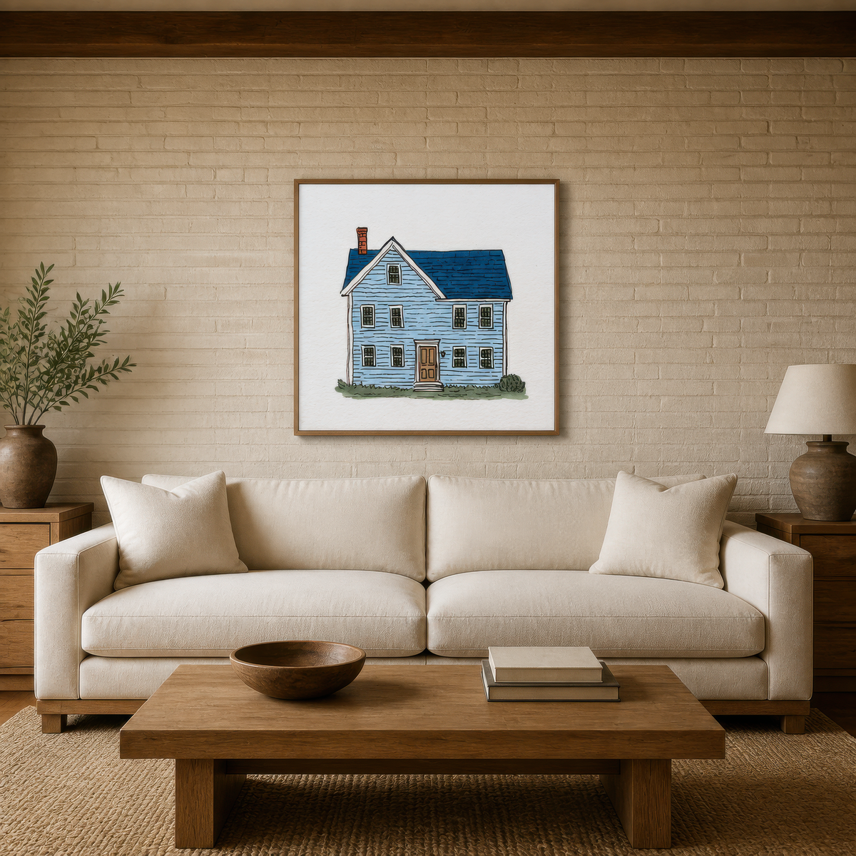 Blue farmhouse illustration above a cream sofa on a pale brick wall with olive branches