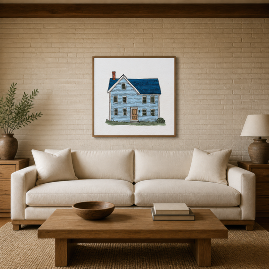 Blue farmhouse illustration above a cream sofa on a pale brick wall with olive branches
