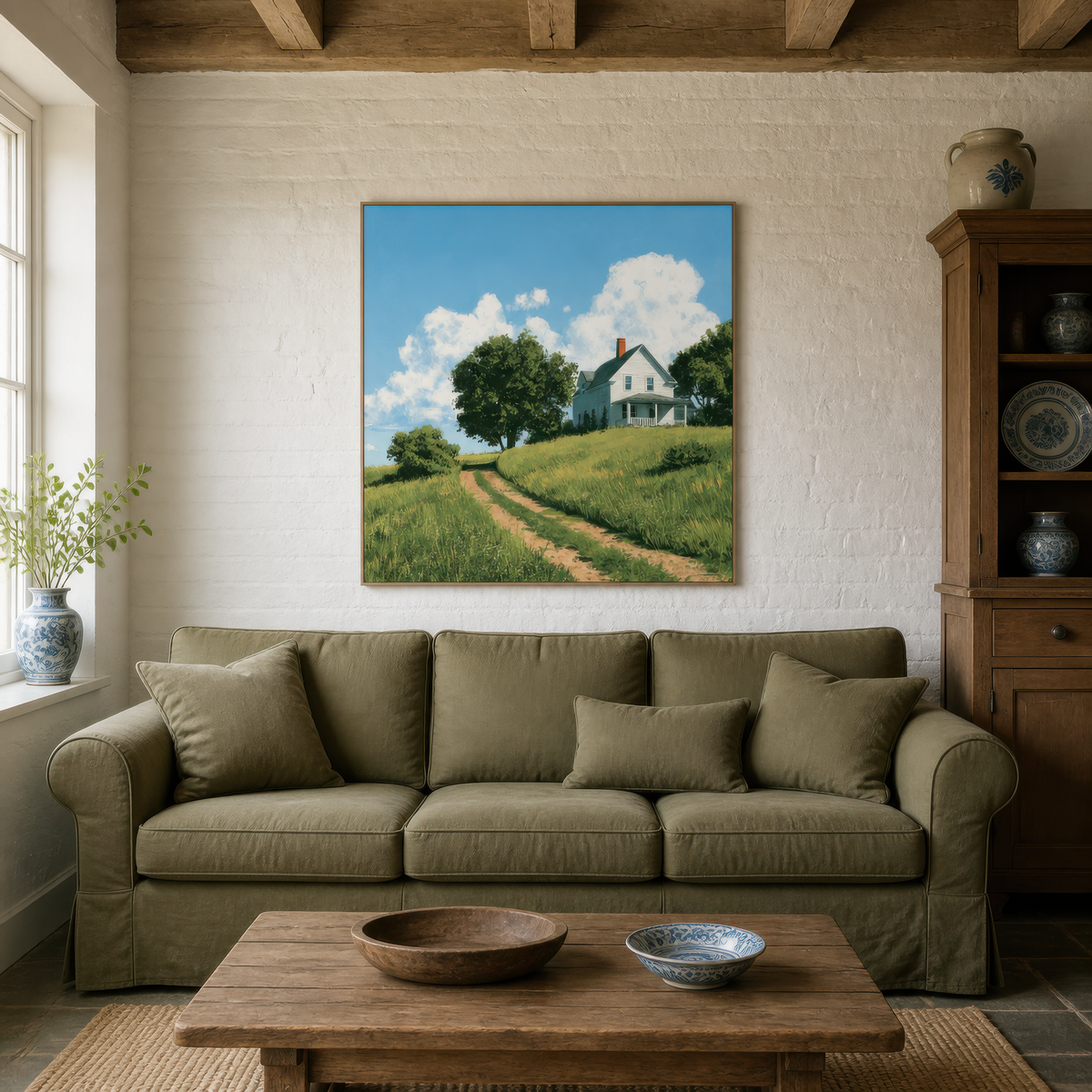Green hillside farmhouse above an olive green sofa with a wood table and a glazed cabinet